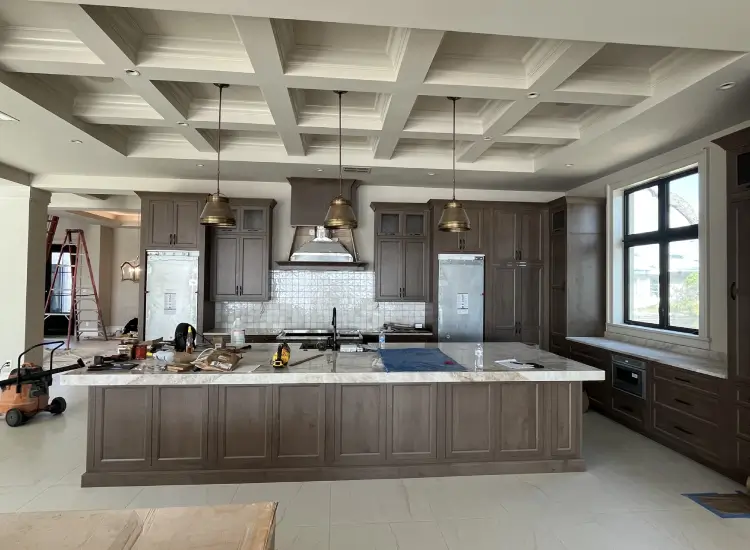 modern coastal kitchen with coffered ceiling and waterfall marble island new construction