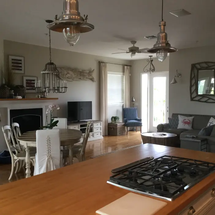 Coastal transitional open-concept interior design in Fort Myers featuring rustic lighting, warm wood flooring, and layered living spaces